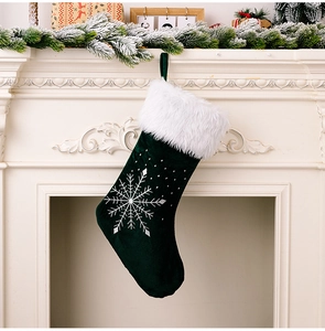 Gros plan d'une chaussette de Noël en velours avec broderie flocon d'argent sur cheminée