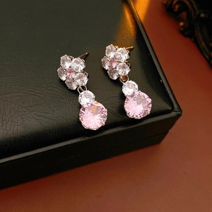 Close-up of pink zircon flower earrings with rose gold plating on a black jewelry box