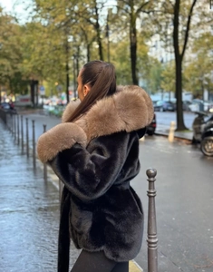 Détail macro du manteau en fausse fourrure noire avec une grande capuche en fourrure brune