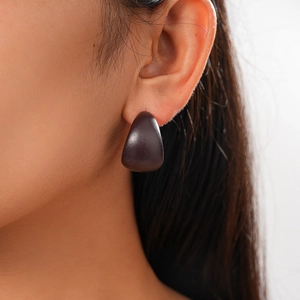 Close-up of deep purple droplet resin earring worn on ear with minimalist C-shape design