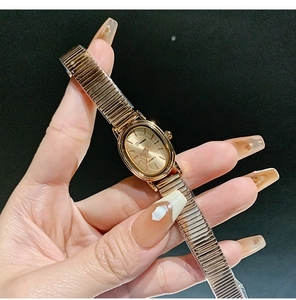 Detailed view of an oval gold quartz watch featuring a sleek elastic metal mesh band