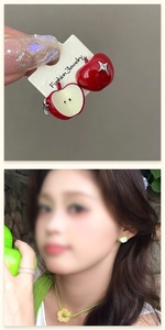 Detail of asymmetrical red apple earrings showing both whole and sliced fruit designs