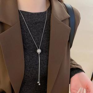 Detailed view of silver adjustable necklace with zircon paved sphere pendant and tassels