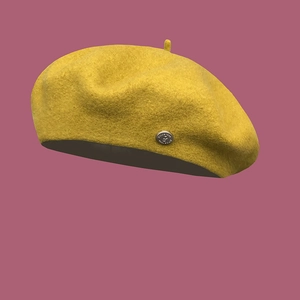 Detailed texture of bright yellow wool beret with small metallic decorative buckle detail