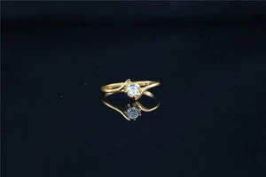 Detail of bypass moissanite ring with round cut diamond on black reflective base