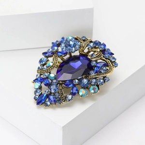 Detail of vintage gold brooch featuring teardrop blue crystal and rhinestone accents