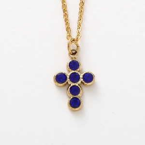 Close-up of golden cross pendant with six round blue crystals on a thin O-chain