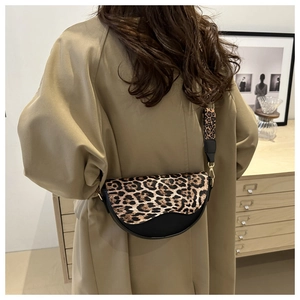 Detail of saddle bag with leopard print flap and wide shoulder strap on model