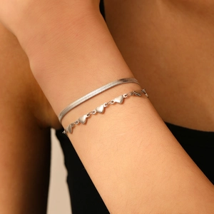 Gros plan d'un bracelet double épaisseur en acier inoxydable argenté avec breloques cœur