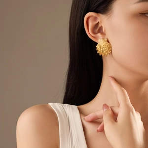 18K gold plated shell earrings featuring detailed nautical texture on model