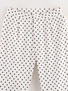 Détails d'un pantalon blanc à pois noirs à taille haute avec des plis élégants à la taille