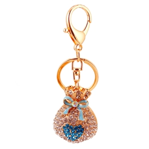 Sparkling crystal money bag keychain with blue rhinestones and gold plating on white background