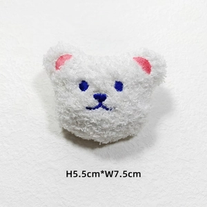 Close-up of white plush bear head accessory with blue embroidery, size 5.5cm x 7.5cm