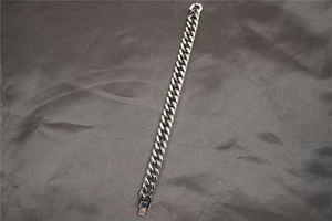 Vista macro di un bracciale a catena cubana d'argento su seta grigia