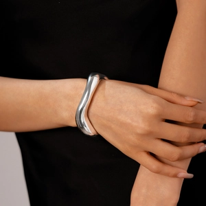 Dettaglio del bracciale rigido argento ondulato con finitura metallica lucida