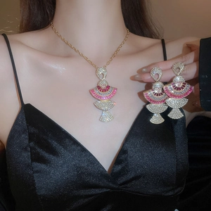 Close-up of fan-shaped necklace and earrings with pink and clear crystals on model