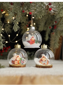 Detalle de tres bolas de Navidad LED con miniaturas luminosas de cabañas y renos