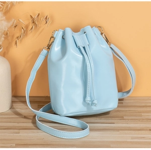 Detail of light blue bucket bag with drawstring closure and elegant golden hardware