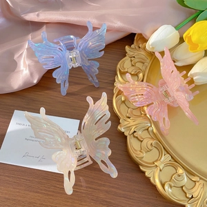 Three iridescent acrylic butterfly hair claws in blue, pink, and beige for women