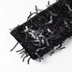 Detailed close-up of sequin tassel cuffs on a black tweed mini dress with metallic sheen