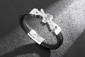 Macro shot of a black braided leather bracelet with silver skull charms and a polished clasp