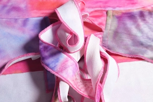 Detailed macro view of tie-dye fabric texture and pink overlock stitching on the strap