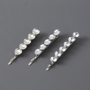 Macro detail of three silver metal hair clips featuring sparkling heart and round rhinestones