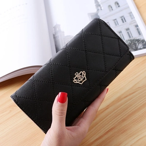 Close-up of black quilted long wallet with golden crown emblem held by hand
