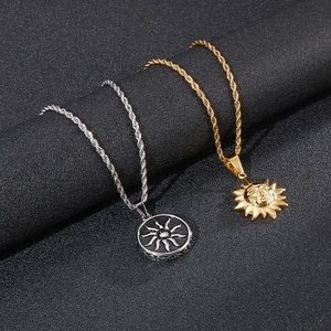 Gros plan de pendentifs soleil en or et argent avec chaînes torsadées sur fond noir