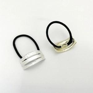 Detail of gold and silver metallic curved charms on premium black elastic hair ties