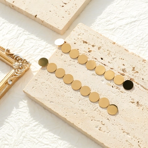 Detailed close-up of golden geometric tassel earrings on vintage prop stones