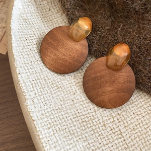 Detailed close-up of wood and amber resin geometric earrings on a ceramic tray