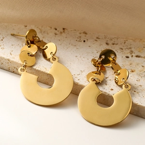Modern gold geometric titanium steel earrings displayed on a natural stone textured background
