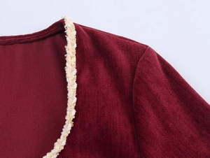 Detailed view of burgundy velvet shoulder with gold braided trim and pearl button accents
