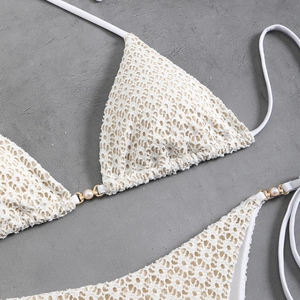 Close-up of white lace crochet bikini top featuring pearl and gold metal accents