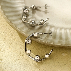 Detail of silver C-shaped stainless steel earrings with metallic bead accents