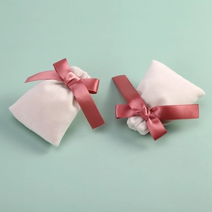 Detail view of velvet jewelry pouches with elegant ribbon bows on soft green background