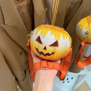 Detail of pumpkin-shaped crossbody bag with festive smiley face and wide graphic strap