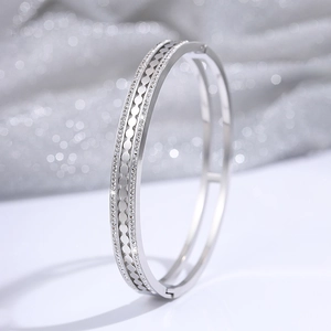 Macro detail of silver titanium steel hinge bangle with hollow geometric patterns and gems