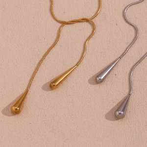 Detailed macro view showing gold and silver teardrop pendants on sleek snake chains