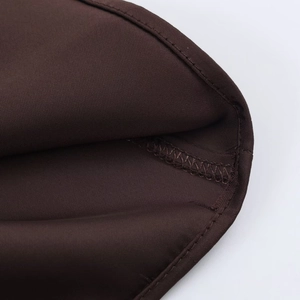 Detail of dark brown satin shirt fabric with neat edge stitching and premium texture