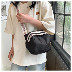 Close-up of black nylon crossbody bag with colorful jacquard wide shoulder strap detail