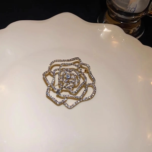 Detail of gold-plated rose brooch featuring sparkling white zircons and hollow design