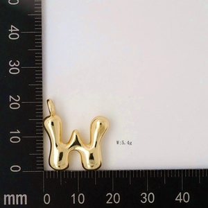 Macro shot of 3D balloon letter W pendant in polished gold with size measurement scale