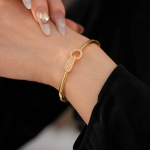 Detailed close-up of gold-plated bangle with keyhole design and pave-set zircons