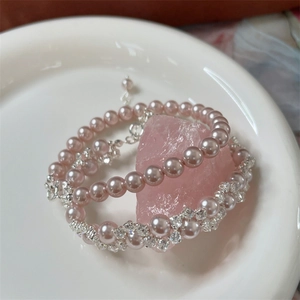 Close-up of pink pearl and zircon woven bracelet with silver clasp on crystal base