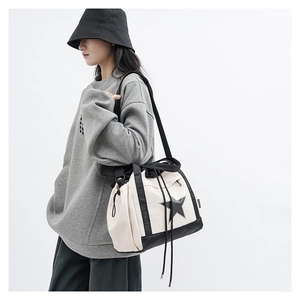Model wearing a cream-colored crossbody tote bag with a bold black star print