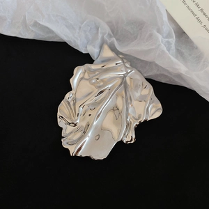 Macro shot of silver leaf brooch with folded texture and mirror polished finish