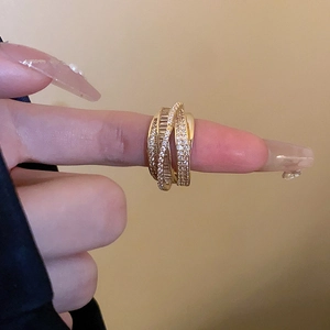 Macro shot of layered gold crossover ring with round and baguette zircon inlay detail