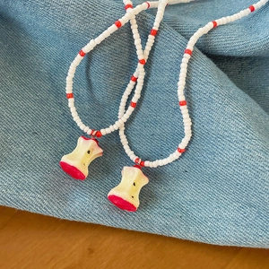 Summer beaded necklace with resin apple pendant on denim and wood background